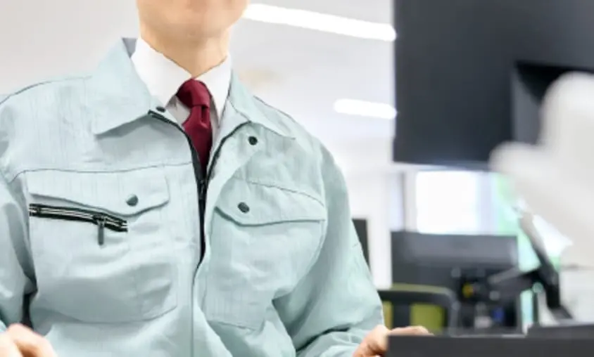作業服を着た社員がパソコンに向かって仕事をしている様子